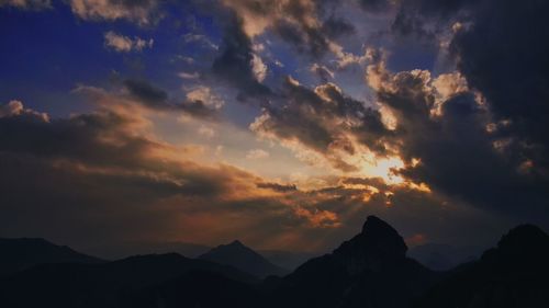 Low angle view of silhouette mountains against dramatic sky