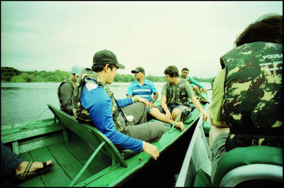 People sitting on boat in sea against sky