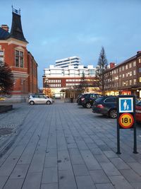 Cars on street against illuminated buildings in city at dusk