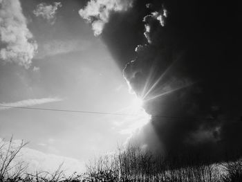 Low angle view of sun shining through clouds