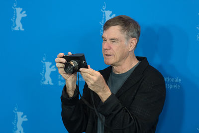 Man holding camera against blue wall