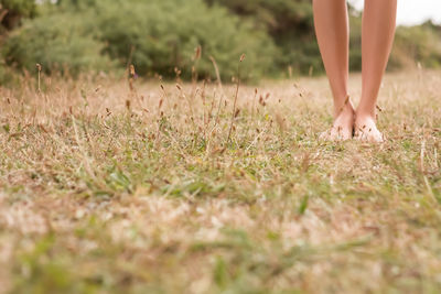 Low section of woman standing on field