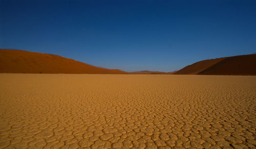 Scenic view of desert against clear blue sky