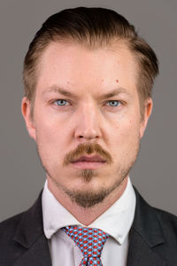 Close-up portrait of young man against gray background