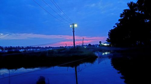 Reflection of electricity pylon in lake against sky