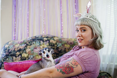 Young woman wearing bunny ears holding a dog