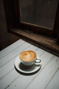 Latte art coffee on wooden table in coffee shop