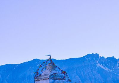 Low angle view of cross on mountain against clear sky