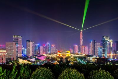 Illuminated buildings in city against sky at night