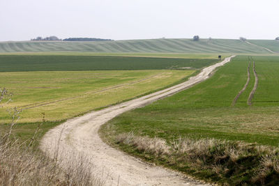 Road amidst field against clear sky