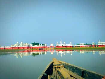 Reflection of built structure in water against clear blue sky