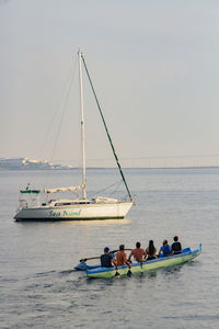 People on sailboat in sea against sky