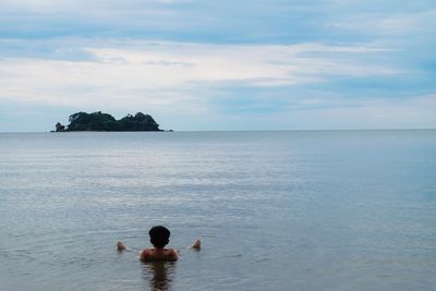 Rear view of man in swimming pool against sky