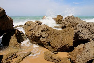 Rocks on beach against sky at ocean