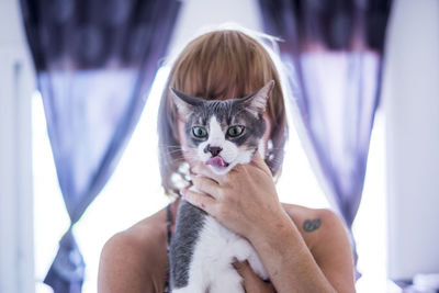 Woman covering face with cat at home