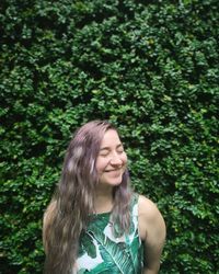 Young woman smiling while standing against trees