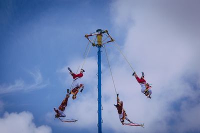 Low angle view of people hanging against sky