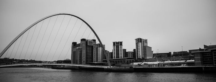 Bridge over river in city against clear sky