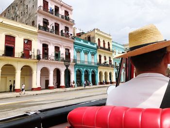 Rear view of man wearing hat while riding convertible car in city