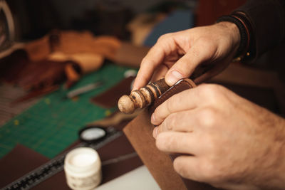 Wooden tool. tanner makes leather wallet, professional craftsman, closeup, indoors, authentic, 