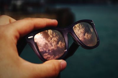 Cropped hand of person holding sunglasses