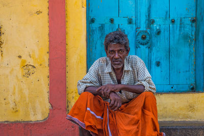 Portrait of man sitting against wall