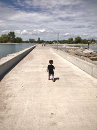 Rear view of toddler boy walking on dam in canada