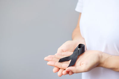 Midsection of woman holding gift against gray background