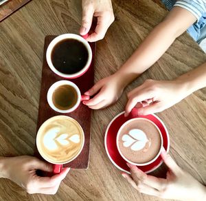 High angle view of woman holding coffee cup on table