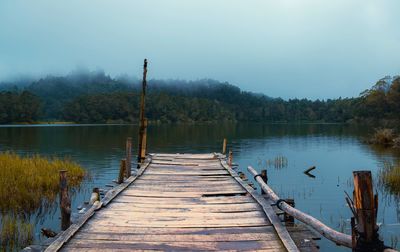 Wooden pier over lake against sky