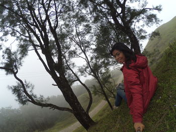 Full length of young woman standing by tree