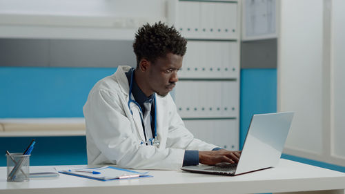 Young doctor using laptop at clinic