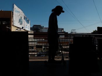 Silhouette man standing in city against clear sky