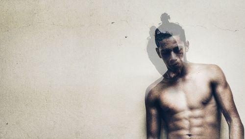 Double exposure of shirtless man against wall