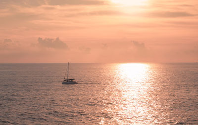 A sailboat playing in the sea at sunset