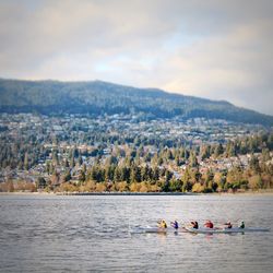 People enjoying in sea against mountain range