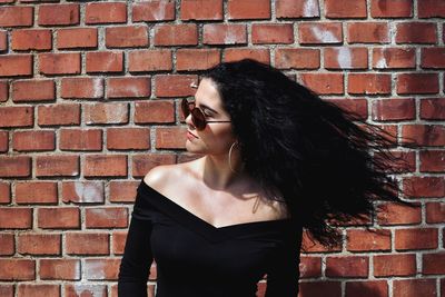 Woman standing against brick wall