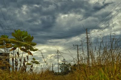 Electricity pylon against cloudy sky