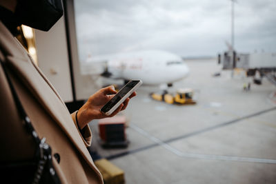 Cropped hand of woman using smart phone at airport