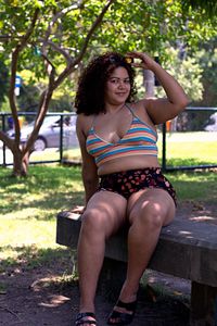 Portrait of young woman sitting on bench in park