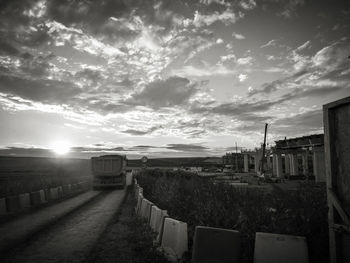 Road by street against sky during sunset