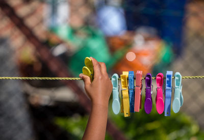 Cropped image of hand pinning clothespin on clothesline