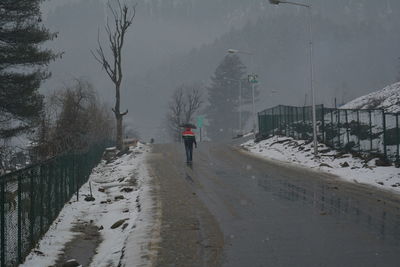Rear view of man walking on snow covered mountain