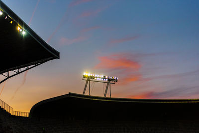 Glowing stadium lights against sunset sky during blue hour