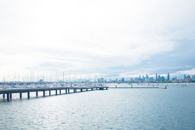 Pier over sea against sky in city