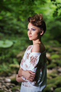 Portrait of young woman standing against trees