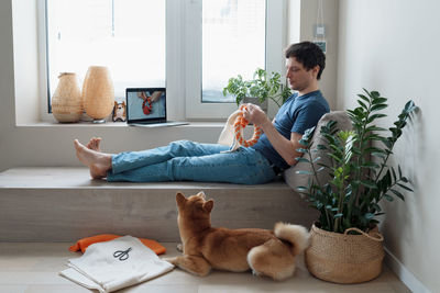 Adult man making diy homemade educational toys for dogs using a tutorial from the internet