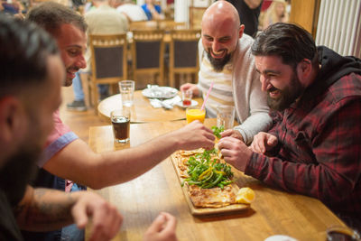 Happy friends having food at table