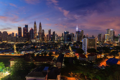 Illuminated modern buildings in city against sky