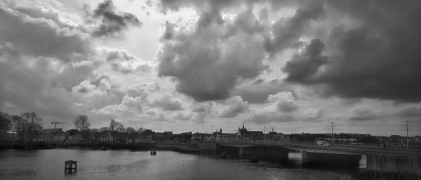 Bridge over river in city against sky